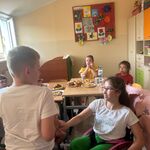 Uczniowie siedzą przy stole i jedzą urodzinowe przekąski.