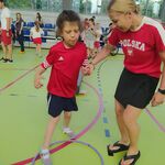 Uczennica z pomocą nauczycielki wykonuje zadanie sportowe.