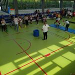 Widok sali gimnastycznej ze społecznością szkolną biorącą udział w imprezie.