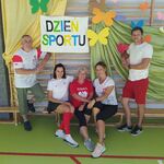 Trzy nauczycieli w WF siedzą na ławce. Po bokach stoją nauczyciele.