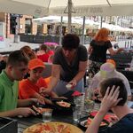 Uczestnicy szkolnych półkolonii siedzą przy stolikach w pizzerni.
