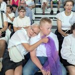 Uczniowie w świątecznych strojach siedzą na ławce.