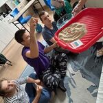 Uczeń wkłada gumowego kraba na tacę z piachem.
