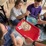 Uczennica wrzuca gumową rozgwiazdę do miski z wodą.