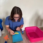 Uczennica przykleja figury geometryczne na kartkę.