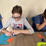 Uczennica przykleja figury geometryczne na kartkę.