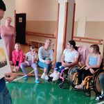 nauczycielka pokazuje obrazek uczniom siedzącym na ławce.