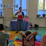 Nauczycielka pokazuje obrazek uczniom siedzącym na ławce.