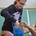 Uczennica szuka w słoiku z hydrożelem niespodzianki.