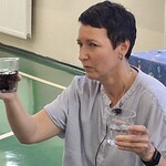 Nauczycielka pokazuje szklanki z czystą i brudną wodą.