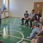 Uczniowie podczas warsztatów, nauczycielka pokazuje butelki z wodą: plastikową i szklaną.