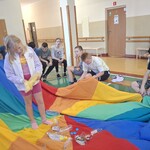 Uczennica stoi na chuście animacyjnej z żółtą torbą. Dookoła siedzą uczestnicy warsztatów.