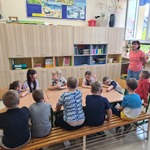 Nauczycielka mówi do uczniów siedzących wokół stolika.