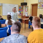 Nauczycielka  pokazuje obrazki i mówi do uczniów.