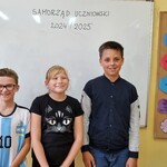 Grupa uczniów stoi przed białą tablicą.