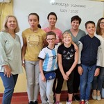 Grupa osób stoi na tle białej tablicy.