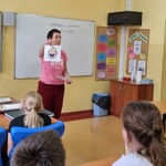 Nauczycielka  pokazuje obrazki i mówi do uczniów.