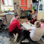 Nauczyciel prezentuje uczniom butelki z kolorowymi płynami.