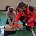 Uczeń ćwiczy masaż serca na fantomie pod kontrolą ratownika medycznego.