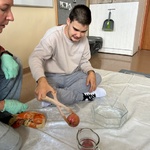 Uczeń wyciąga jabłko z wody drewnianymi nożycami