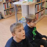 Uczniowie siedzą na podłodze w bibliotece.
