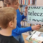Pani bibliotekarka pokazuje uczniowi powiększony druk.