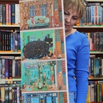 Pani bibliotekarka pokazuje rozkładaną książkę.