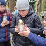 Uczniowie trzymają w rękach znicze.