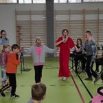 Społeczność szkolna podczas audycji muzycznej zgromadzona na sali gimnastycznej.