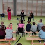 Społeczność szkolna podczas audycji muzycznej zgromadzona na sali gimnastycznej.