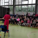 Uczniowie siedzą na ławkach i patrzą na panie prowadzące audycję.