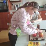 Uczennica wkłada dżem do wydrążonego jabłka.
