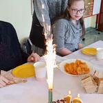 Jubilatka i jej koleżanka patrzą na tort i fontannę tortową - racę.