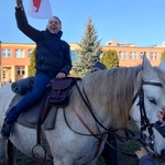 Uczeń siedzi na koniu i trzyma flagą Polski.