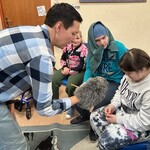 Nauczyciel trzymając pacynkowego jeża wita się z uczennicą.