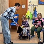 Uczennica wkłada do worka chusteczkę, nauczyciel trzyma worek stojąc przy uczennicy.