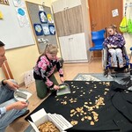Uczennica zamiata suche liście z czarnego materiału.