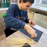 Uczeń przykleja makaron do kartki.