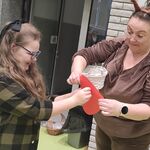 Uczennica przebija czerwone serduszko szpilką trzymane przez nauczycielkę.
