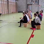 Uczniowie siedzą na ławkach i oglądają występ muzyczny.
