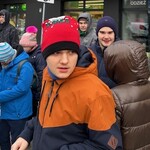 Uczniowie stoją na przystanku czekając na autobus.