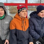 Uczniowie siedzą na przystanku autobusowym.