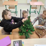 Trzy uczennice ubierają choinkę.