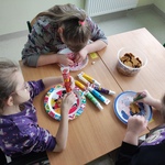 Uczennice siedzą przy stoliku i dekorują pierniki.