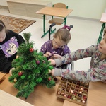 Trzy uczennice ubierają choinkę.