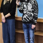 Uczeń czyta tekst. Obok stoi nauczycielka.