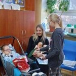 Dziewczynka wręcza pamiątkę dziewczynce na wózku.