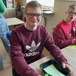 Uśmiechnięty uczeń trzyma pudełko z pracą plastyczną do wykonania