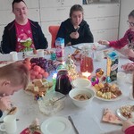 Pani dyrektor, pani zastępca dyrektora oraz uczniowie siedzą przy wigilijnym stole.