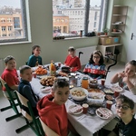 Uczniowie siedzą wokół wigilijnego stołu.